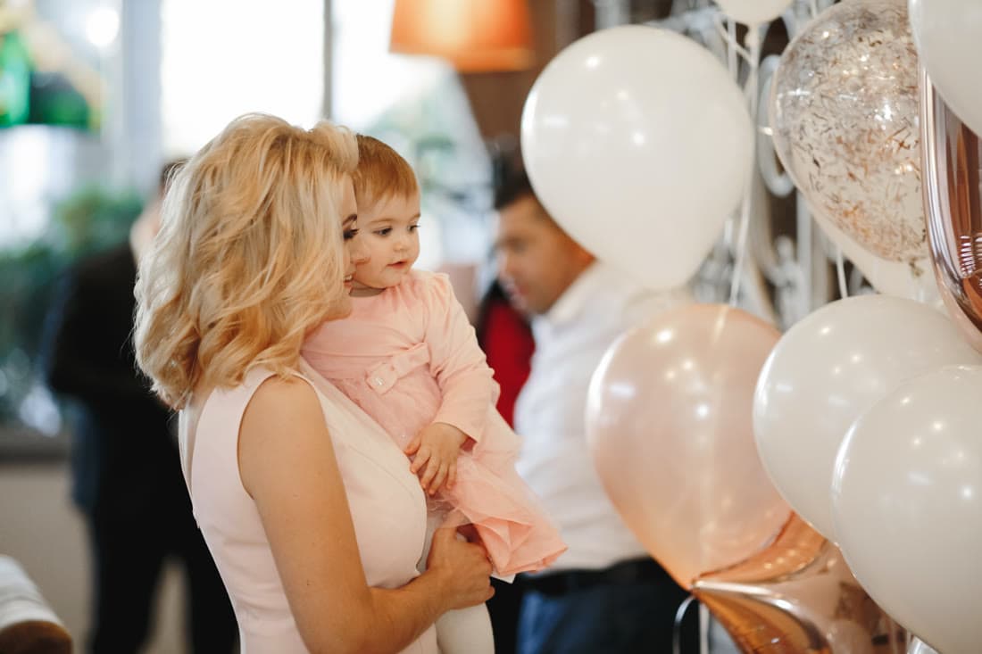 An expectant mother opening a gift surrounded by friends at a baby shower