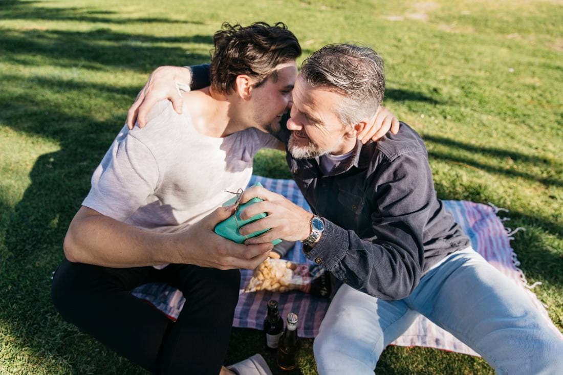 A son hugging his father while giving him a Father's Day present
