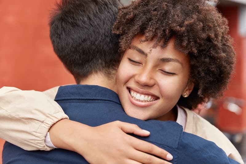 A woman hugging a friend tightly on a doorstep after opening a gift